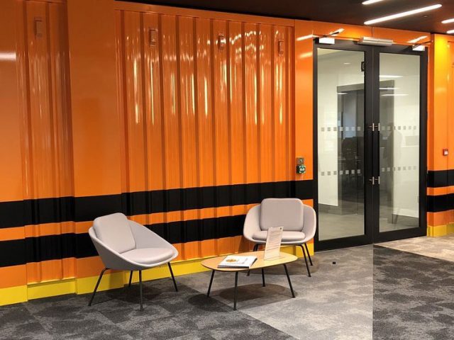 Reception seating area, with a bright orange wall behind.