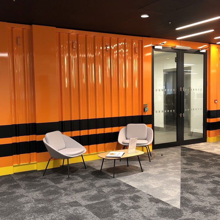 Reception seating area, with a bright orange wall behind.