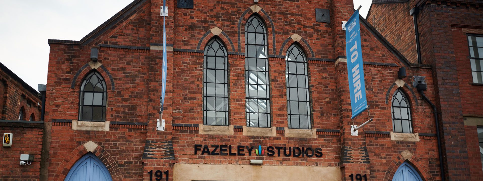 Fazeley Studios logo on old-style building. Banners above the entrance advertise unique event space to hire.