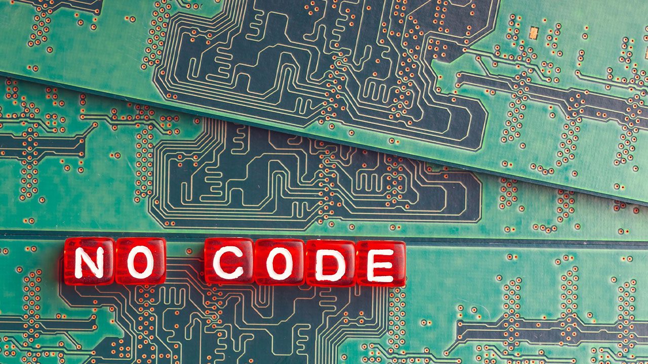 Letter blocks spelling 'No Code' on top of circuit boards.