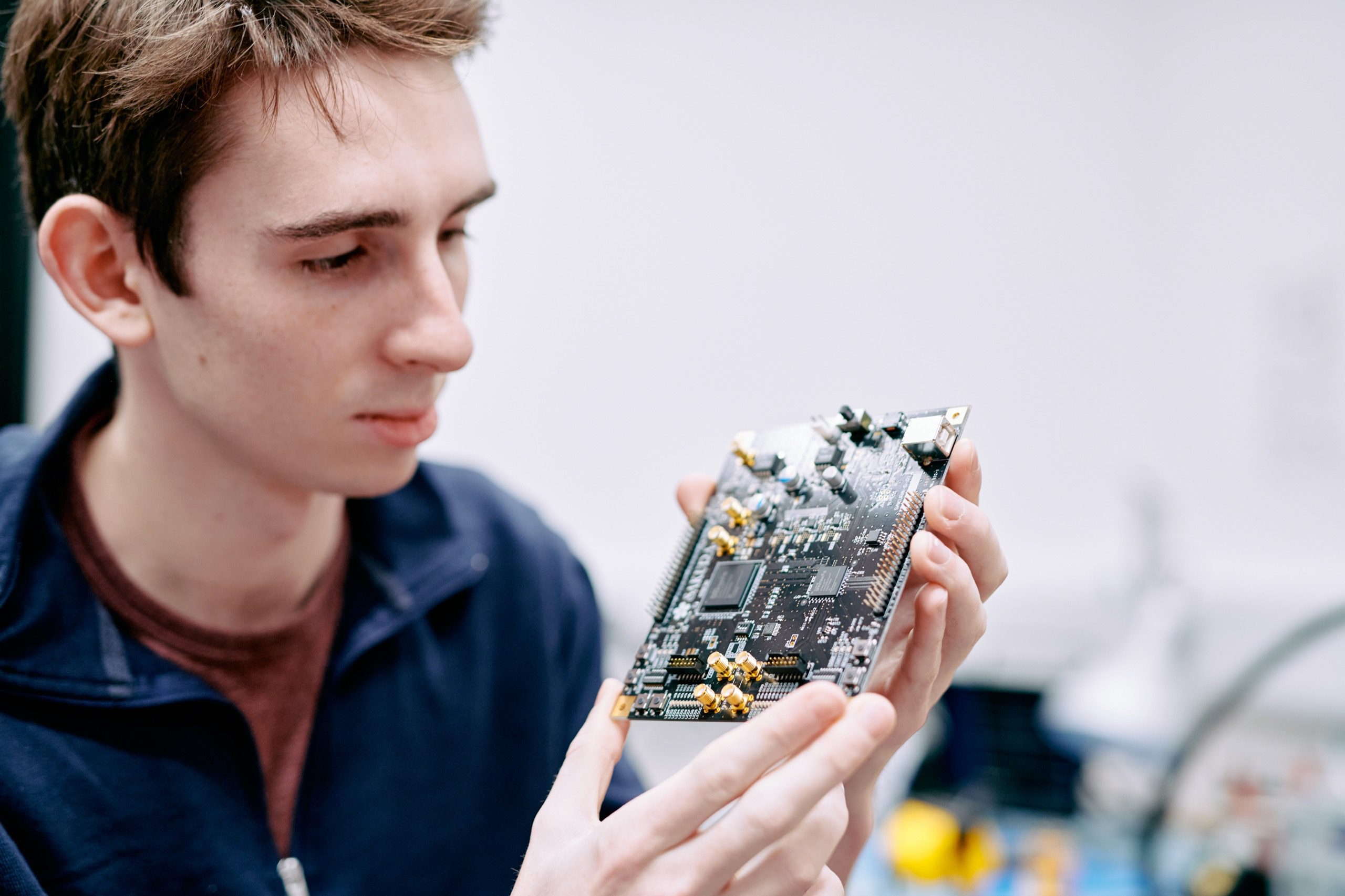 A man holding a circuit board by his fingertips.