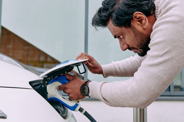 Man plugging in an electric vehicle charger.