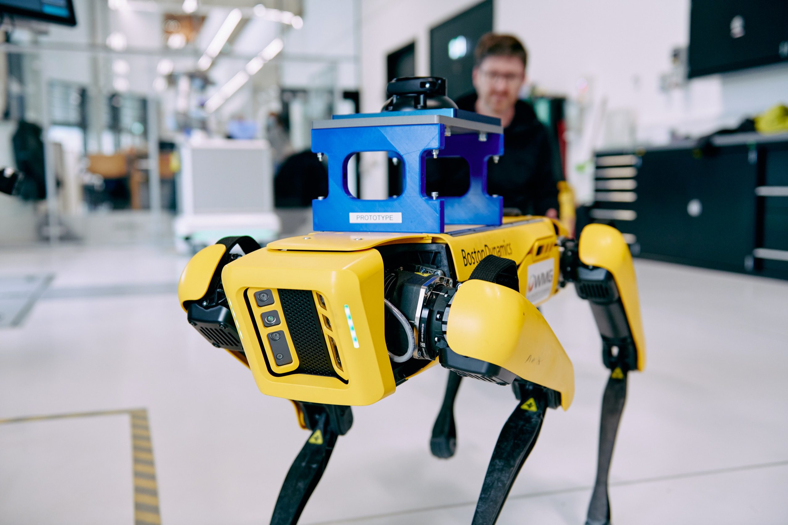 Boston Dynamics Spot robot. Walks on 4 legs like a large dog with a rectangular body.