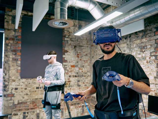 Two people wearing VR headsets and handheld controllers.