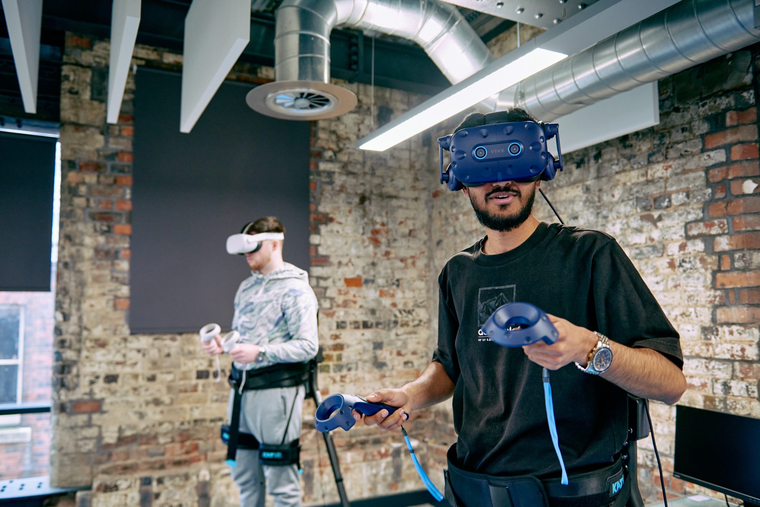 Two people wearing VR headsets and handheld controllers.