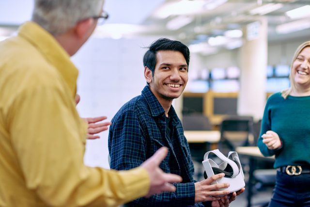 A man smiling and holding a VR headset.