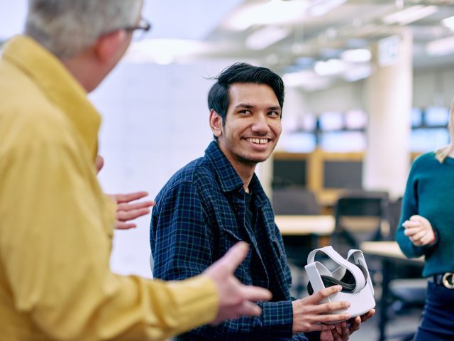 A man smiling and holding a VR headset.