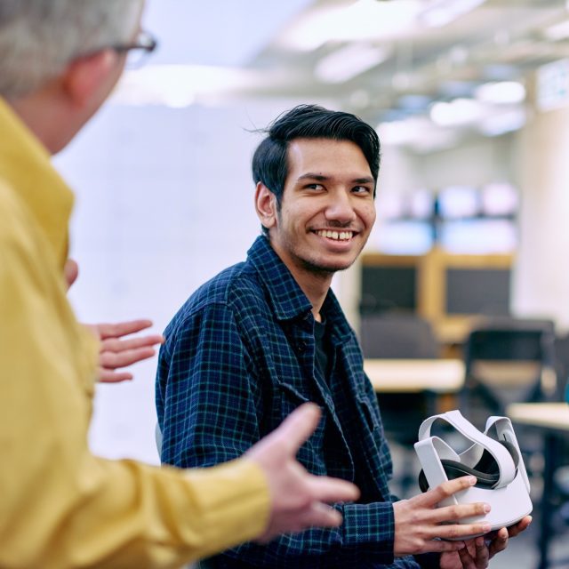 A man smiling and holding a VR headset.