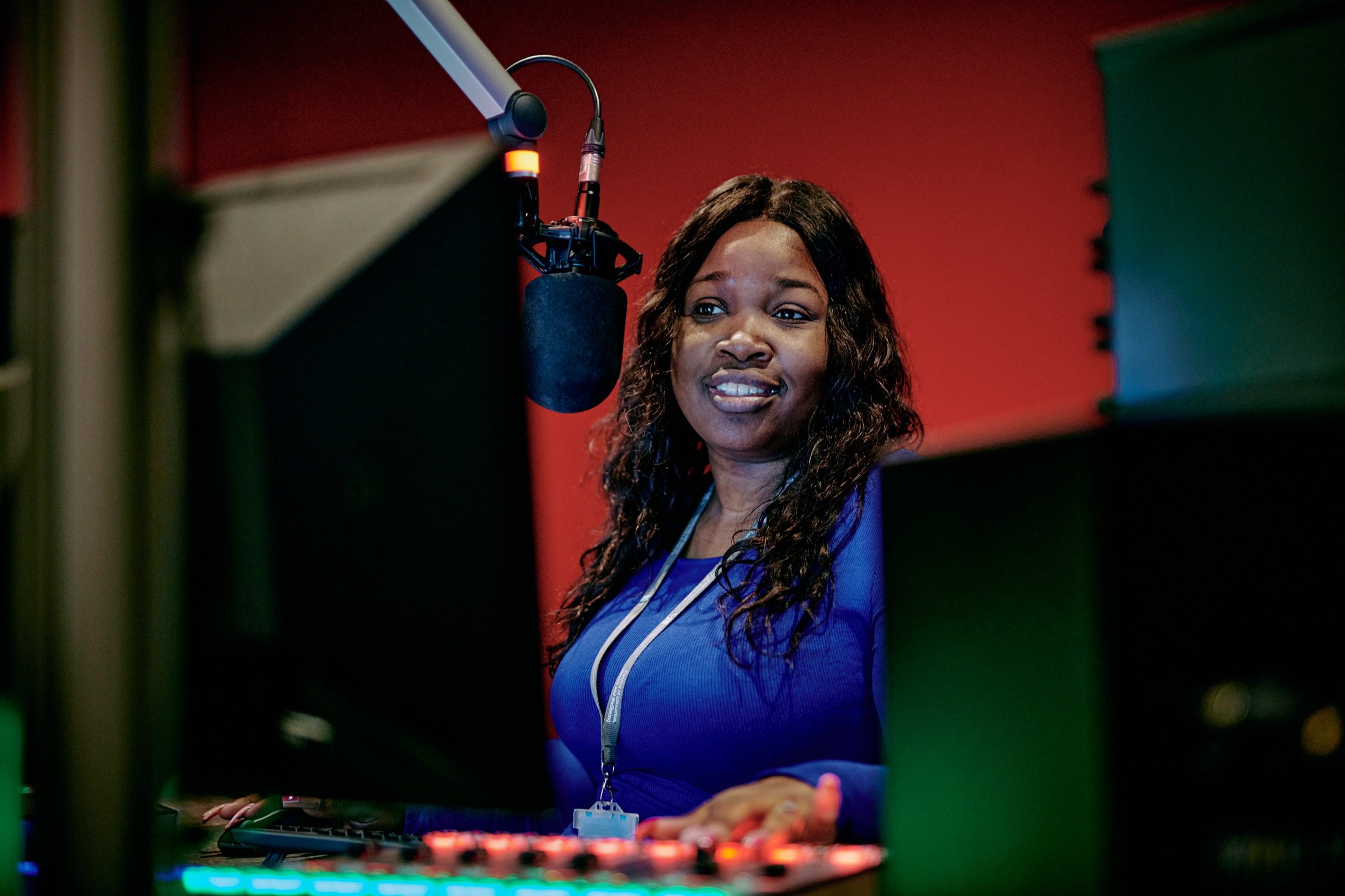 A woman in a recording studio with a microphone in front of her.