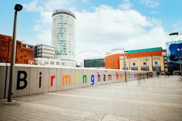 Rainbow coloured letters on the wall spell 'Birmingham New Street Station'.