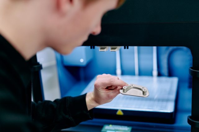 Someone inspecting a 3D printed metal part.