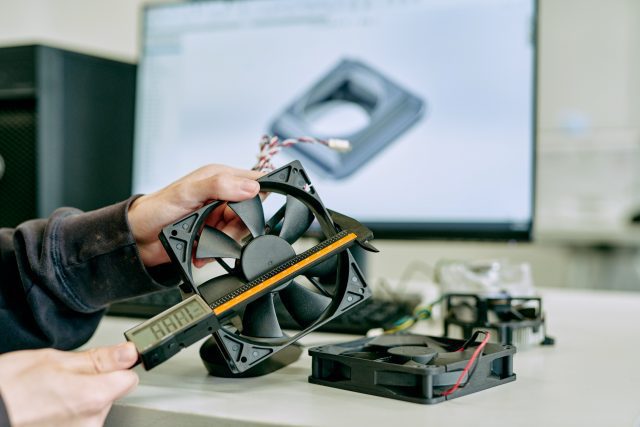 Someone measuring a plastic enclosed fan.