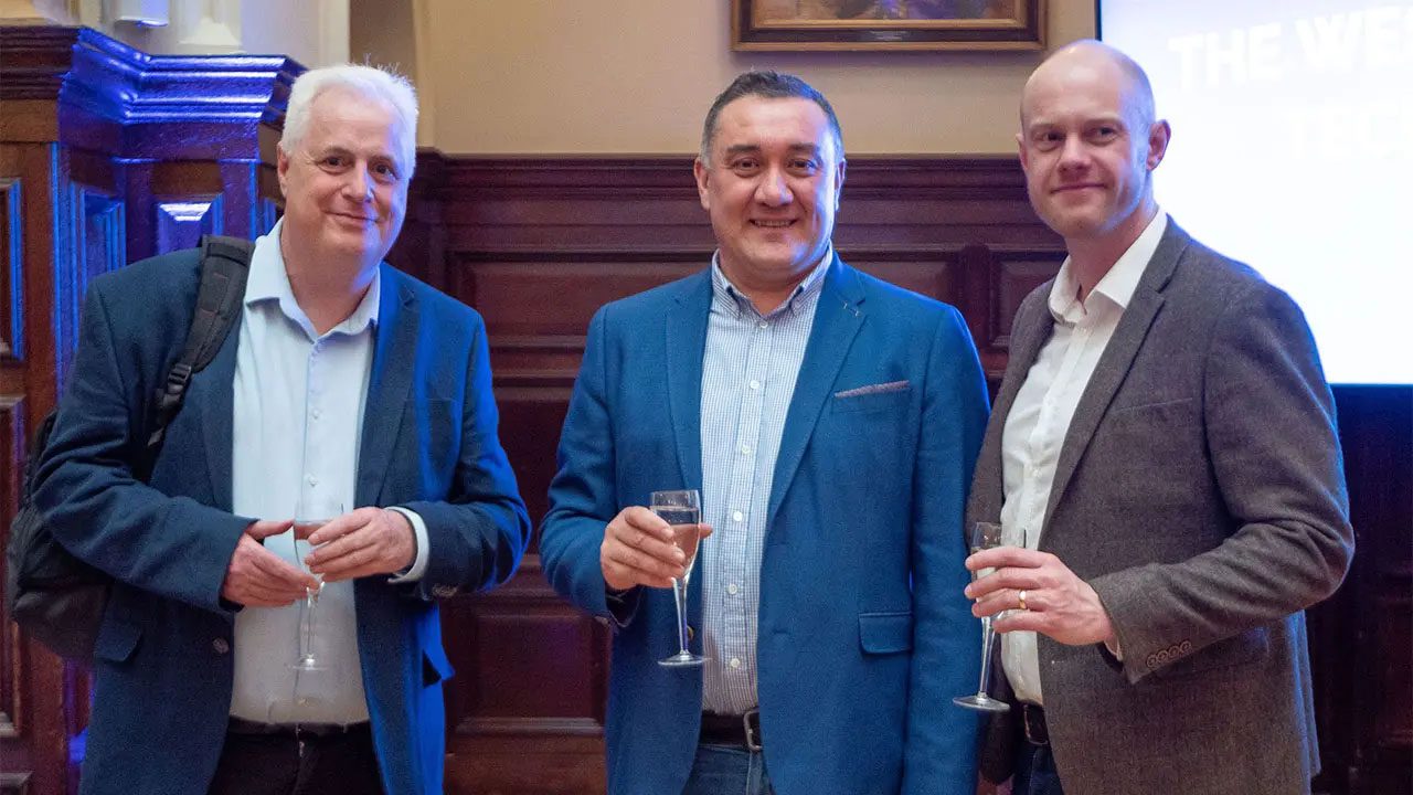 3 men in suits with champagne glasses in hand.