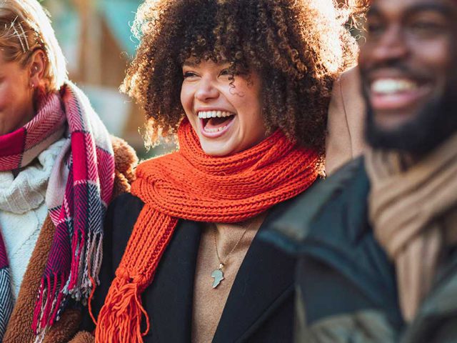 People wearing scarfs and coats, laughing.