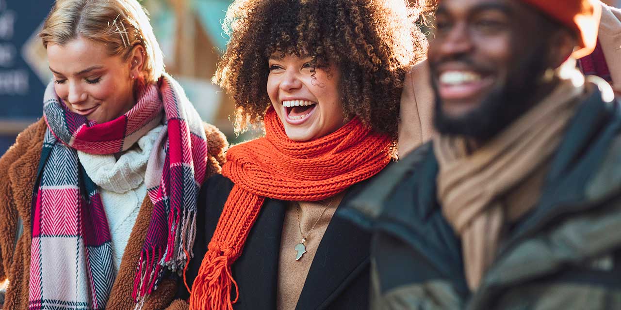 People wearing scarfs and coats, laughing.