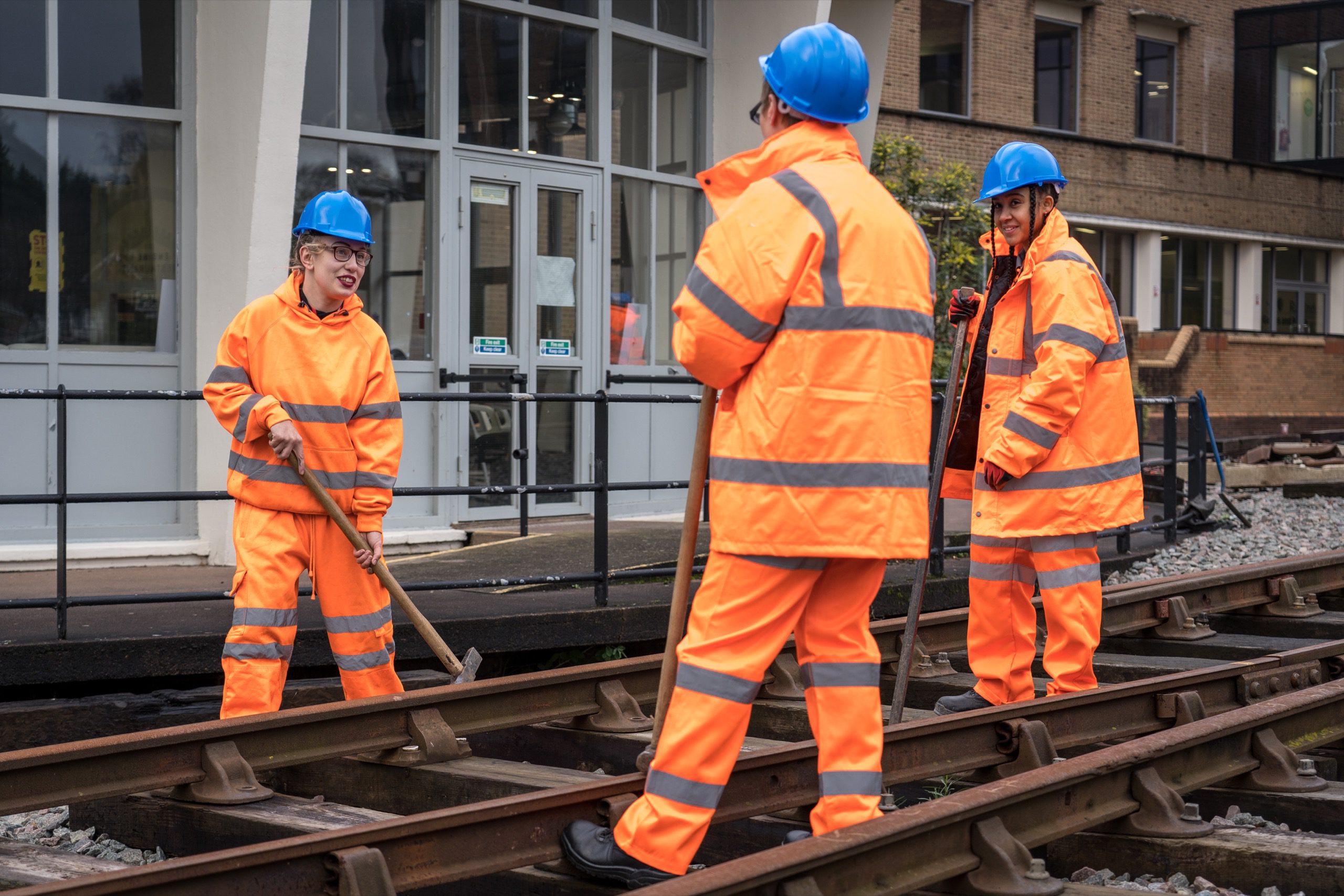 Rail workers standing on tracks, in hi-vis jackets and hard hats.
