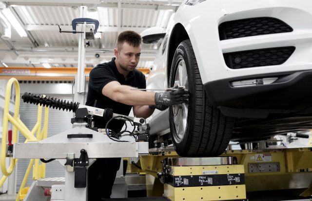 Mechanic measuring the tyres of car, which is up on a ramp.