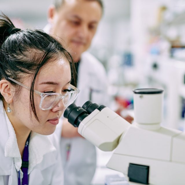 Students inspecting Cancer cells under microscope.