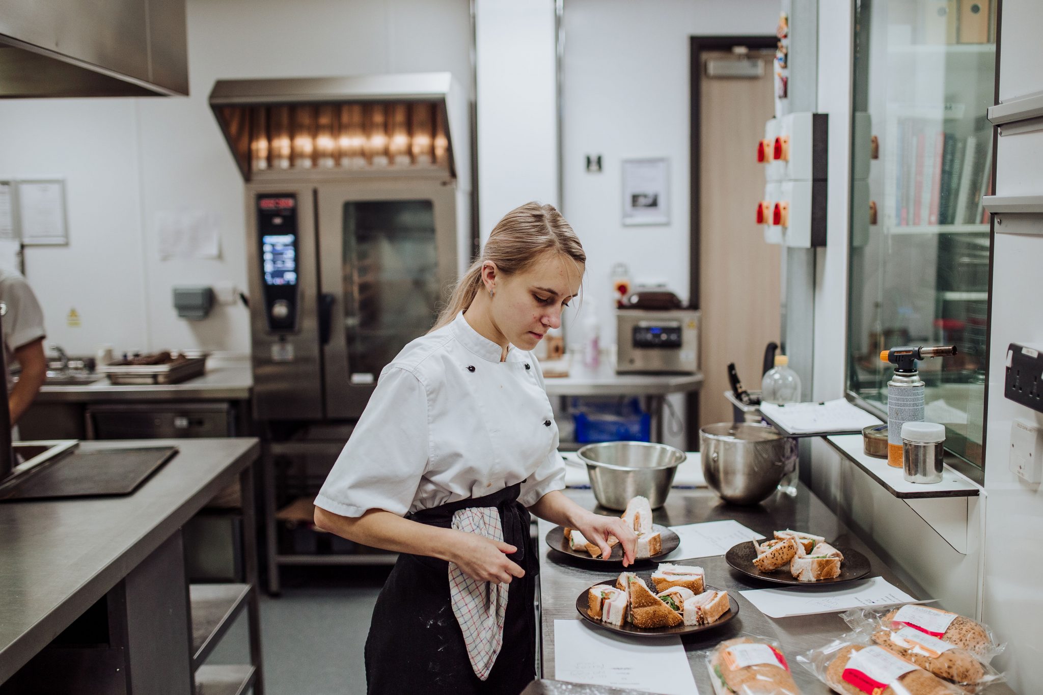 Chef preparing sandwiches in a large kitchen.