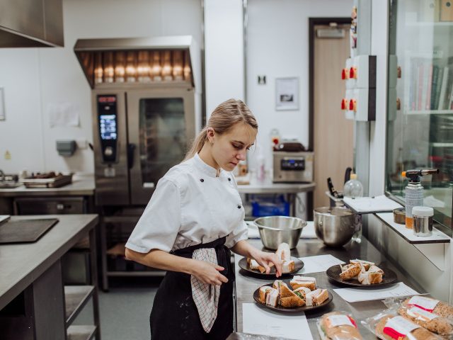 Chef preparing sandwiches in a large kitchen.