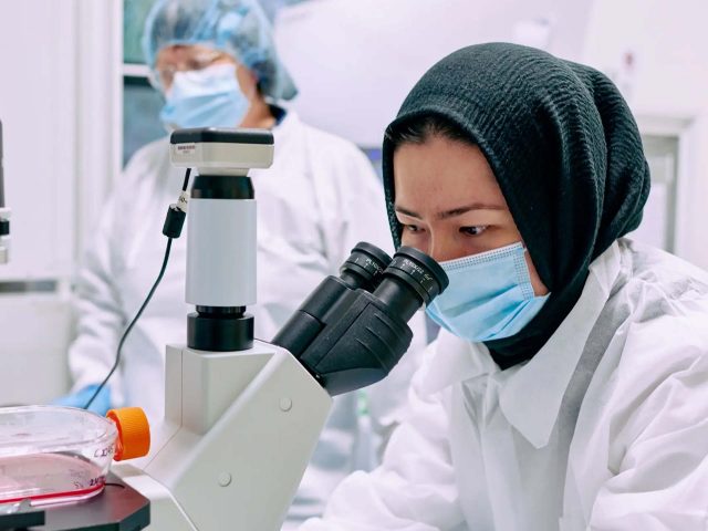 Scientist looking down a microscope.